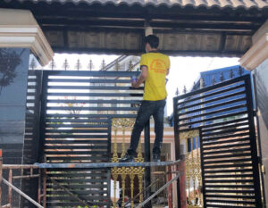thợ đang vệ sinh để sơn cửa cổng